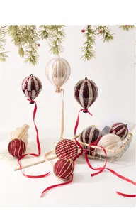 Deep red and champagne hot air balloon Christmas ornaments hanging on a pine branch