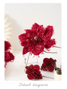 Detailed view of dark red velvet poinsettia flower with gold glitter and paper ornaments