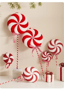 Close-up of red and white spiral Christmas lollipop ornaments with festive bows and glitter