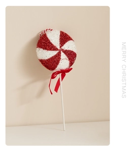 Close-up of red and white striped Christmas lollipop ornament with glitter and ribbon