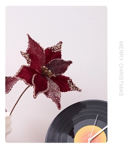 Detailed view of burgundy velvet Christmas poinsettia with glittery gold edges