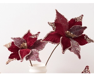Detail of burgundy velvet poinsettias with gold glitter edges in a white ceramic vase