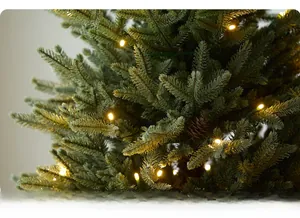Close-up of artificial pencil Christmas tree with warm LED lights and pine cones