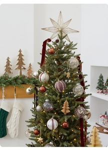 Close-up of artificial green Christmas tree decorated with gold star and red ribbons