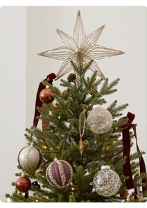 Close-up of a lit golden star topper and elegant mixed Christmas baubles on a tree