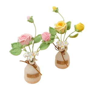 Handgefertigte gehäkelte Rosen-Topfpflanzen mit rosa und gelben Blumen in weißer Basis