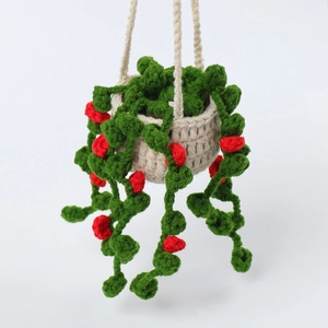 Handmade crochet hanging plant with green vines and red berries in a beige basket