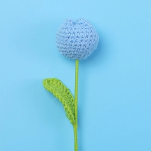 Detail of a handmade blue crochet tulip flower with fine knitted textures and green stem