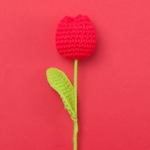 Detailed view of a handmade crochet red tulip flower with realistic knitted texture