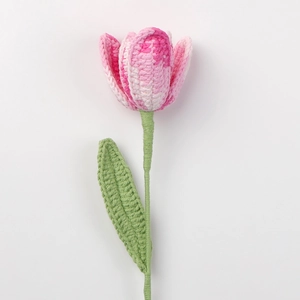 Nahaufnahme einer handgehäkelten Tulpe mit rosa-weißen Blütenblättern und grünem Stiel