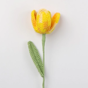 Nahaufnahme einer handgehäkelten Tulpe mit orangefarbenem Farbverlauf und grünem Stiel