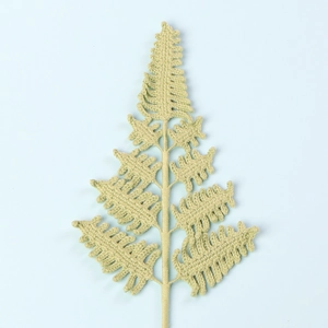 Macro detail of a hand-knitted green fern leaf showing intricate crochet textures