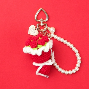 Macro detail of red crochet rose keychain with pearls and heart-shaped metal clasp