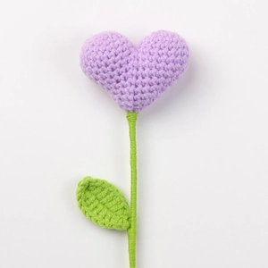 Handmade crochet flower with a purple knitted heart and green leaf on white background