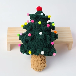 Handmade crochet Christmas tree decor with colorful pompoms on a wooden stool