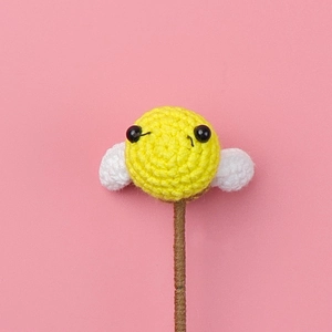 Macro shot of handcrafted crochet bee with white wings on brown stem for DIY gifts