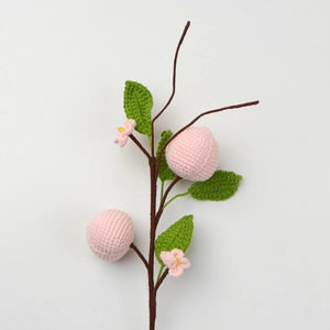 Handcrafted crochet peach blossom branch with pink fruits and green leaves detail