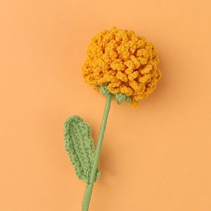 Detailed macro view of a handmade crochet yellow carnation flower with green stem and leaf