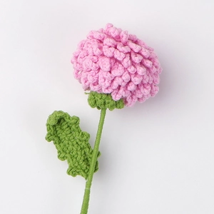 Detailed close-up of pink handmade crochet flower with textured green leaf and stem