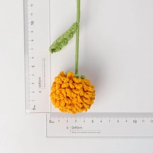 Handmade crochet puff flower in yellow and green with scale ruler for size reference