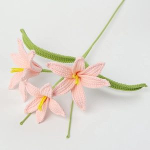 Handmade crochet pink lily with three flower heads and green leaves on white background