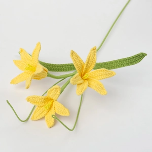 Handmade crochet bouquet with three yellow flowers and green stems on white backdrop