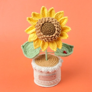 Handmade crochet sunflower plant in cream pot with a cute ladybug decor on a green leaf
