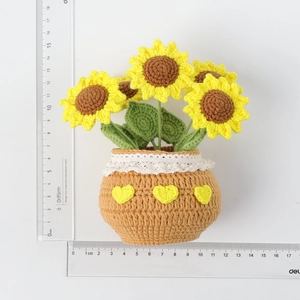 Handmade crochet sunflower plant in a pot with lace trim and rulers for scale
