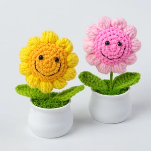 Detail of handmade crochet sunflower and pink flower in white pots with cute smiley faces