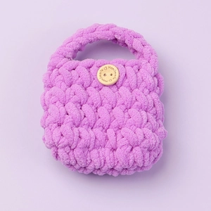 Detail of purple handmade crochet knit case with wooden button and thick yarn texture
