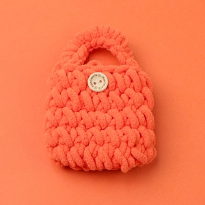 Macro detail of handmade crochet mini bag with a wooden handmade heart button engraving