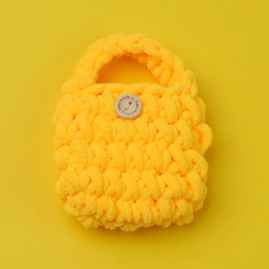 Macro shot of chunky yellow hand-crocheted headphone case with a decorative wooden button
