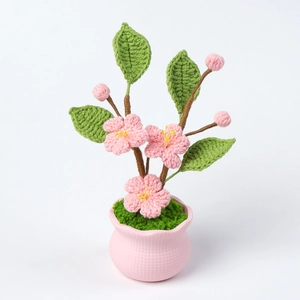Close-up of handmade crochet peach blossom potted plant with pink petals and ceramic pot
