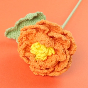 Vue détaillée d'une pivoine orange faite à la main au crochet avec texture en laine