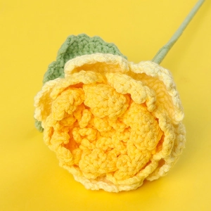 Détail d'une rose crochetée à la main en jaune avec des feuilles et une tige
