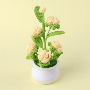 Close-up of handmade crochet flower in white pot showing detailed yellow yarn texture