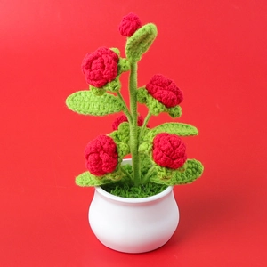 Handmade crocheted red rose potted plant in white ceramic pot as a desktop ornament