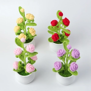 Close-up of four handmade crochet rose plants in ceramic pots with detailed knit texture