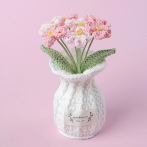 Detail of hand-knitted forget-me-not flower in a white texture pot with handmade label
