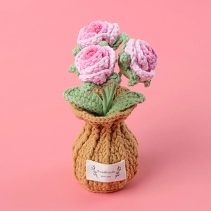 Detail of three pink crocheted roses in a pot with a label stating Handmade WITH LOVE