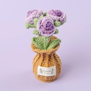 Macro detail of hand-knitted purple roses in a yarn pot with Handmade With Love label
