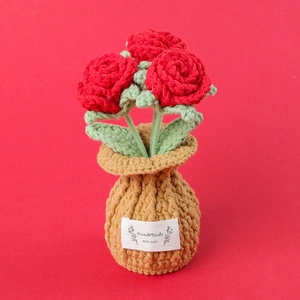 Macro detail of hand-crocheted red rose bonsai in a knit pot with handmade label