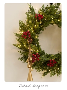 Détail de couronne de Noël avec baies rouges, pommes de pin et quatre cloches dorées
