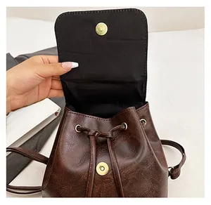Detail of vintage brown leather backpack showing magnetic snap closure and drawstring cord