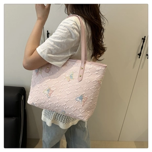 Detail of pink tote bag featuring quilted texture and colorful butterfly embroidery