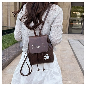 Detail of dark brown faux leather mini backpack with cute cat design worn by a model
