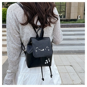 Close-up of black leather mini backpack with cute cat face print and drawstring closure