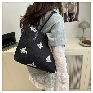 Detail of black quilted tote bag featuring colorful sequin butterfly embroidery and strap