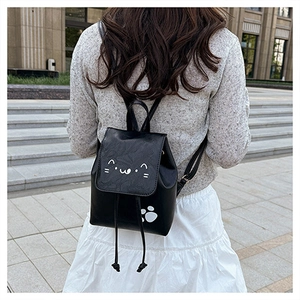 Close-up of black synthetic leather backpack with cute cat embroidery on a female model