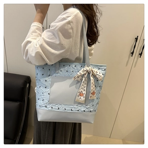 Vue d'épaule du sac cabas matelassé bleu clair avec imprimés nœuds et foulard décoratif